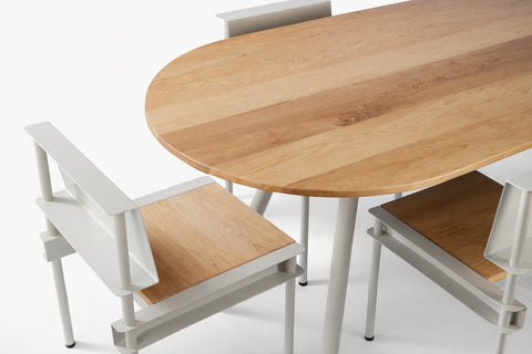 Vista superior parcial del comedor Pilote con cubierta ovalada de madera maciza y sillas a juego en metal y madera.